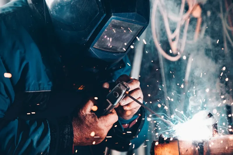 Welder with pipes in background